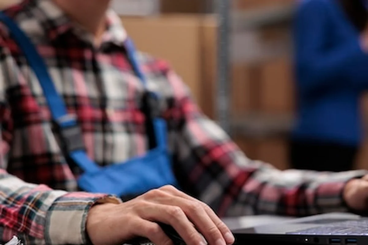 Młody azjatycki menedżer logistyki analizuje dostawy na laptopie. Pracownik magazynu zarządza zapasami na komputerze