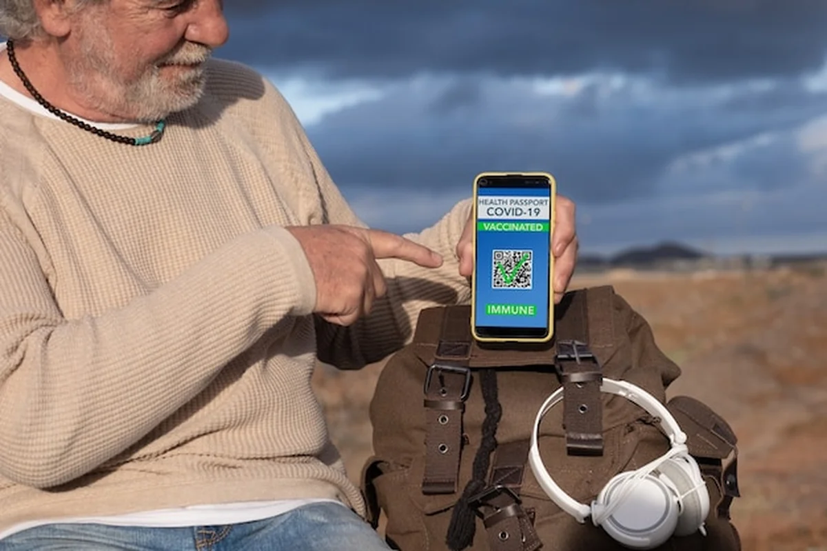 Starszy mężczyzna z zieloną przepustką w aplikacji mobilnej, podróżnik z plecakiem