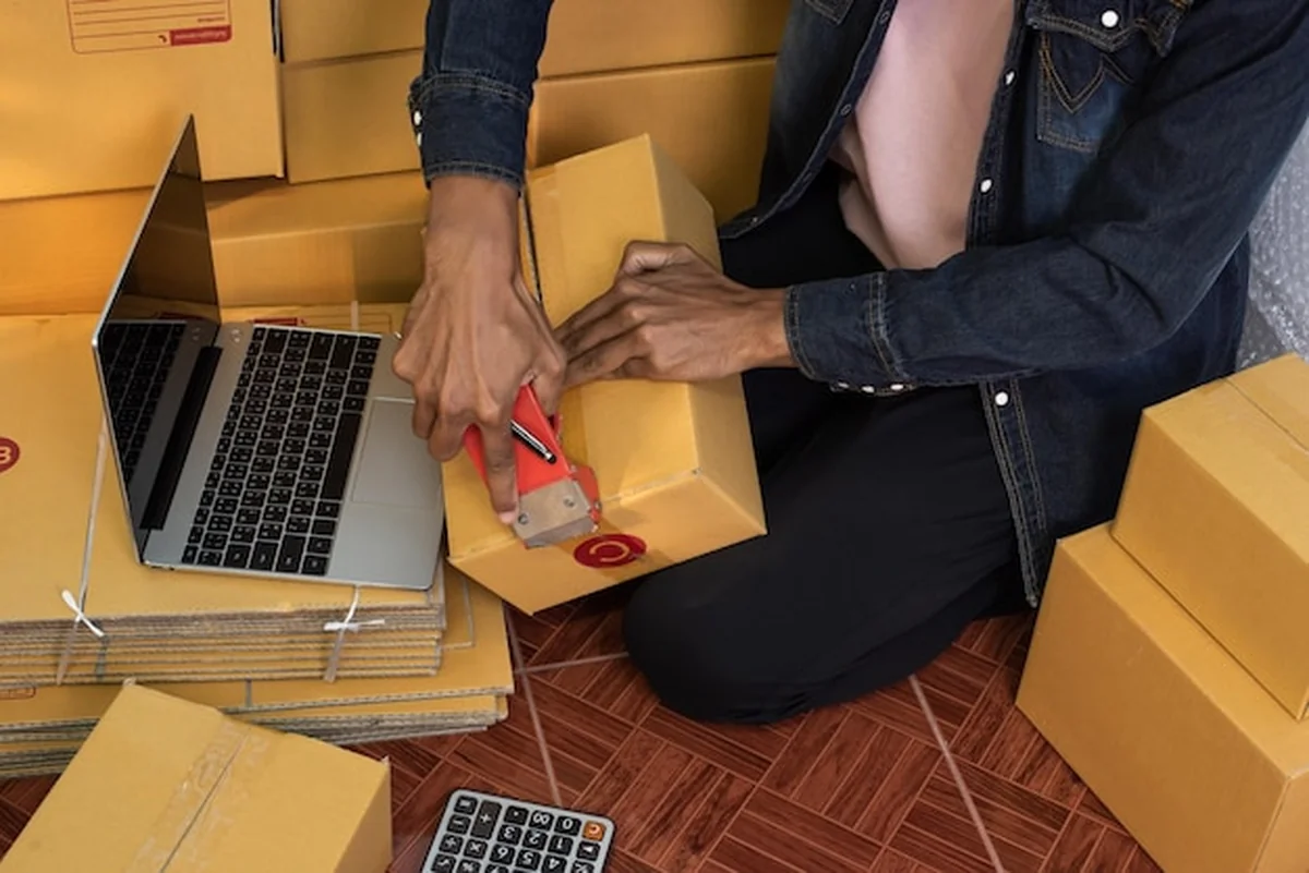 Mężczyzna pakujący paczkę w biurze sprzedaży internetowej