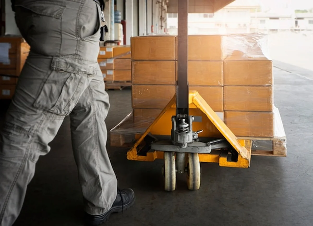 Pracownik magazynu rozładowuje opakowanie w pudłach