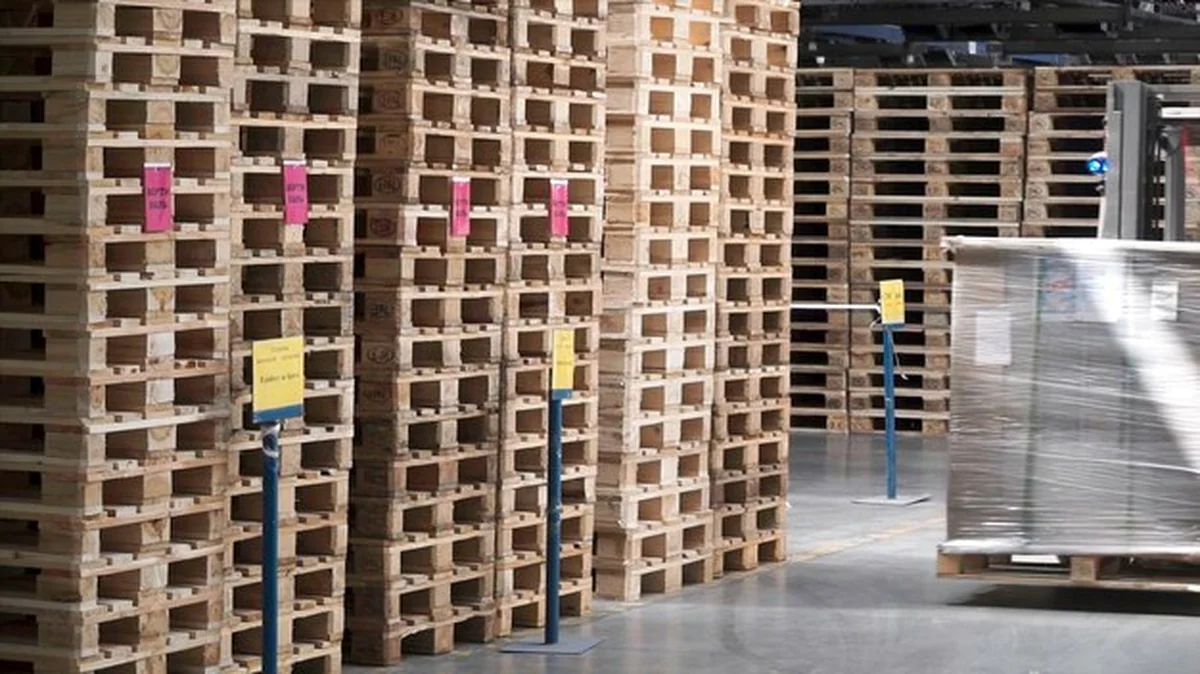 Magazyn z regałami i półkami wypełnionymi kartonami owiniętymi w folią