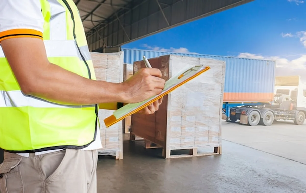 Pracownik trzymający schowek kontroluje wysyłkę ładunku