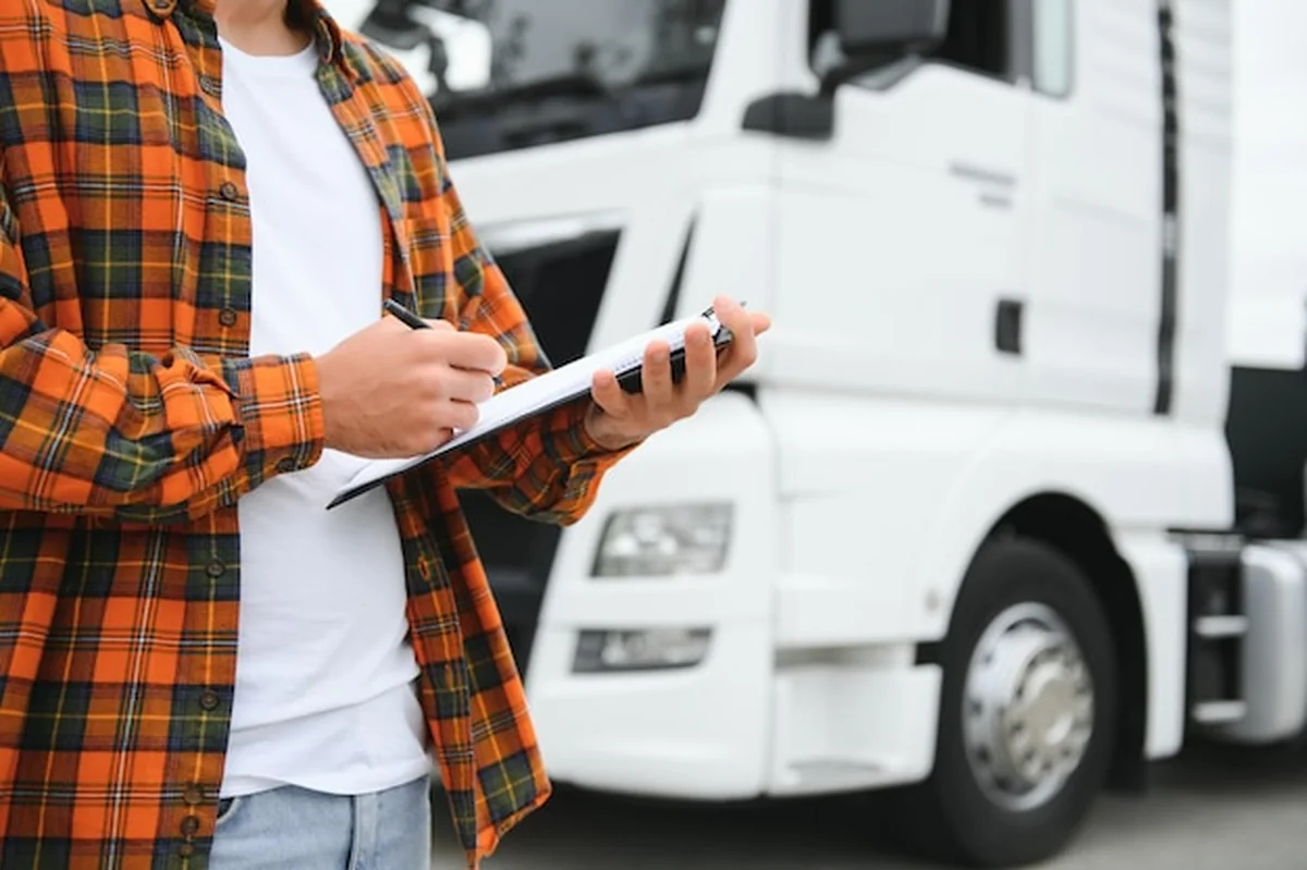 Kierowca ciężarówki sprawdza listę przesyłek na parkingu magazynu