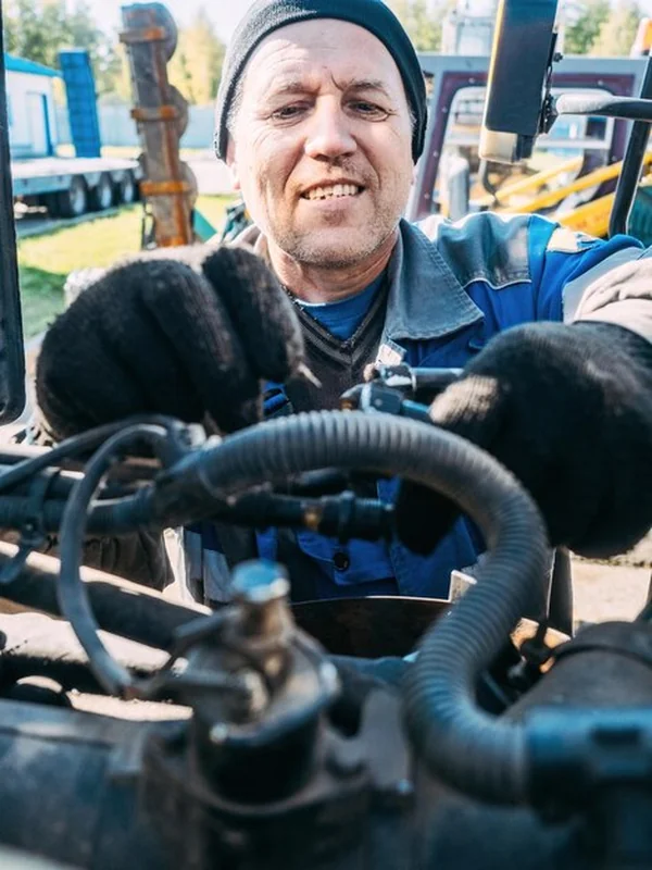 Mechanik naprawia silnik ciągnika, rolnik sprawdza rolnictwo