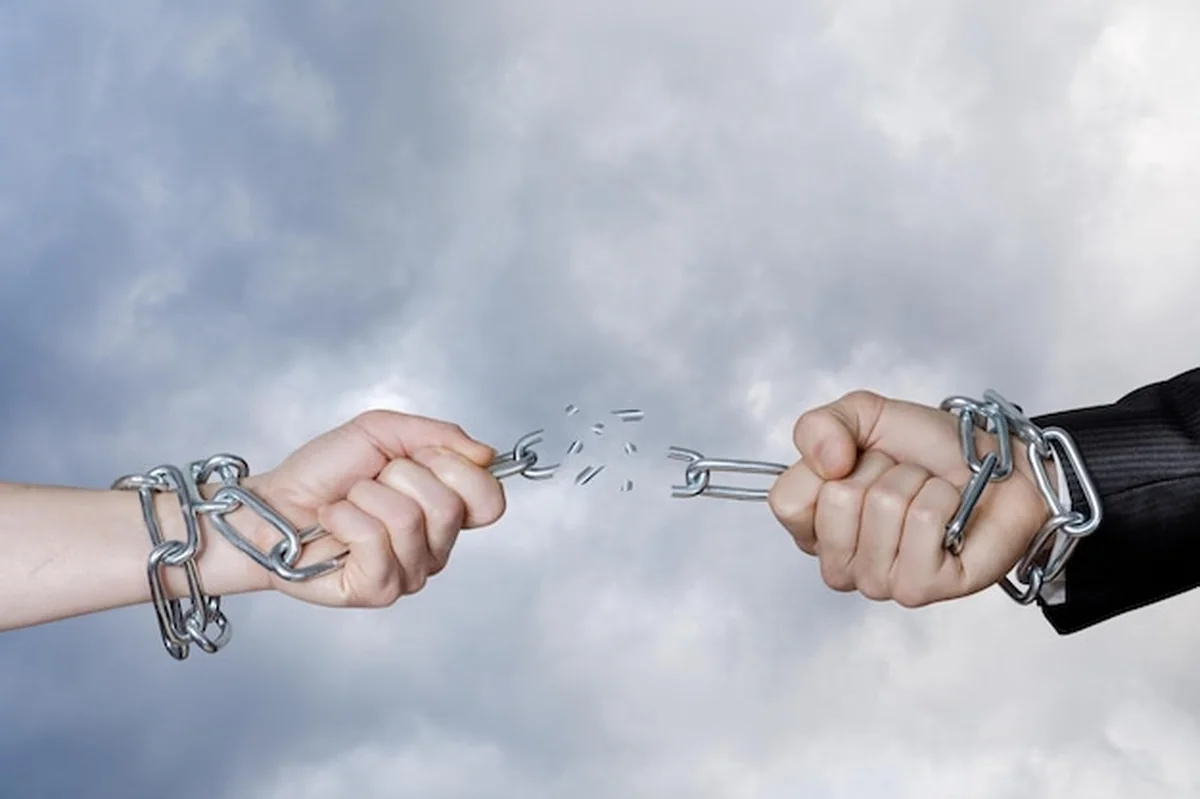 Ręce przerywają łańcuch na tle nieba