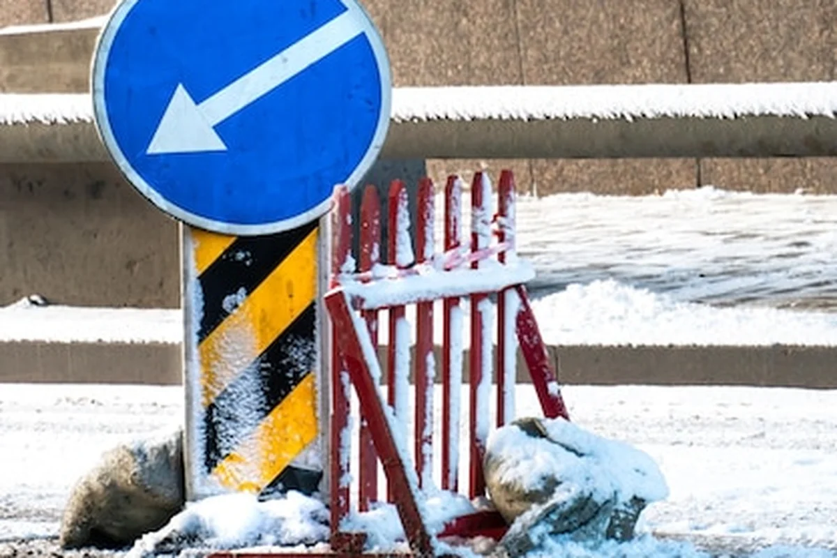 Znak drogowy z białą strzałką na niebieskim tle na jezdni