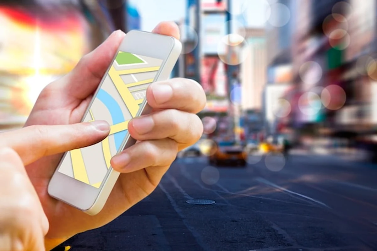 Człowiek korzystający z aplikacji mapy na telefonie przed ulicą Nowego Jorku