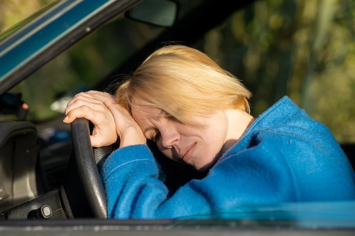Zmęczona kobieta kierująca samochodem po czterdziestce