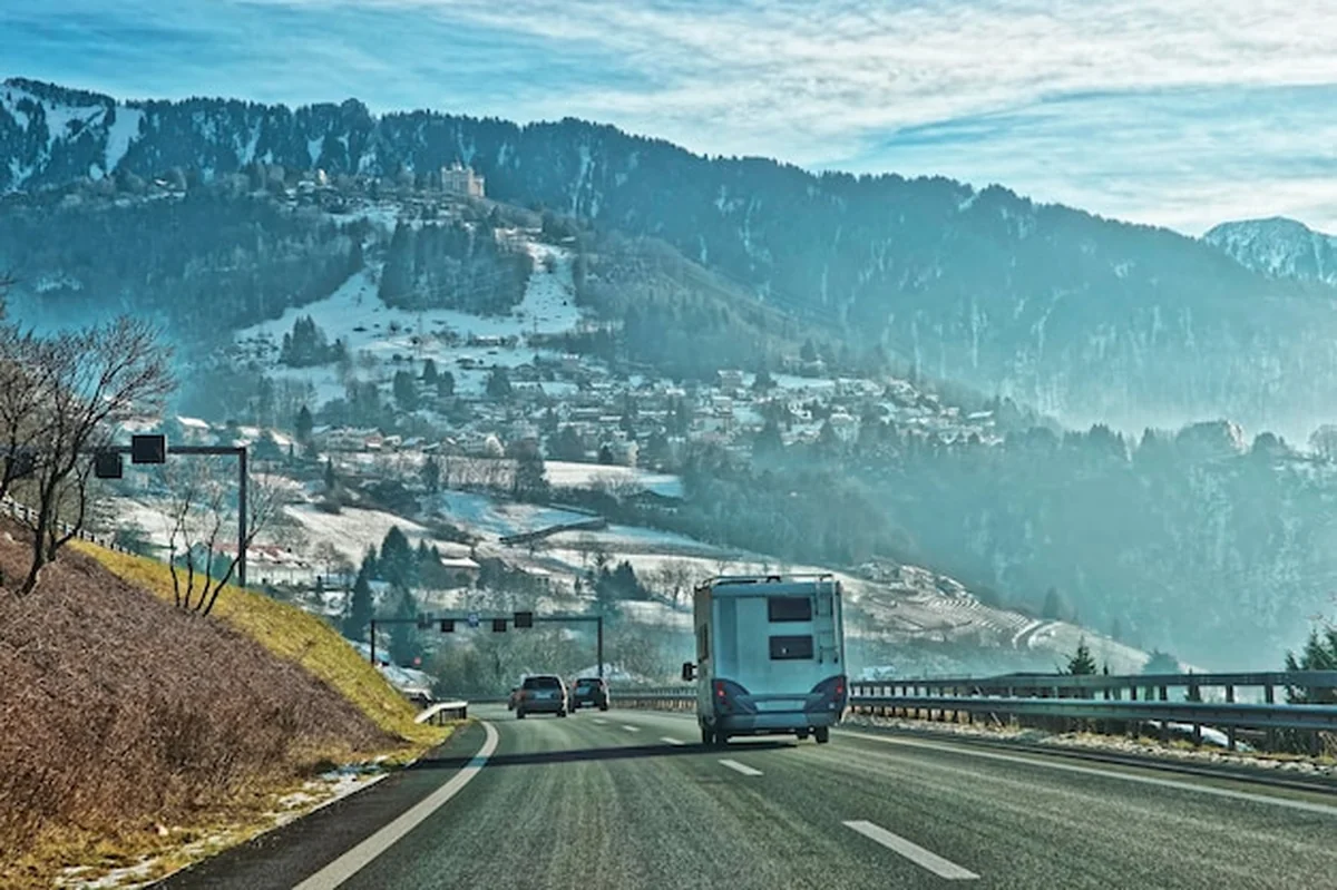 Droga w Szwajcarii z przyczepą kempingową zimą, w tle góry