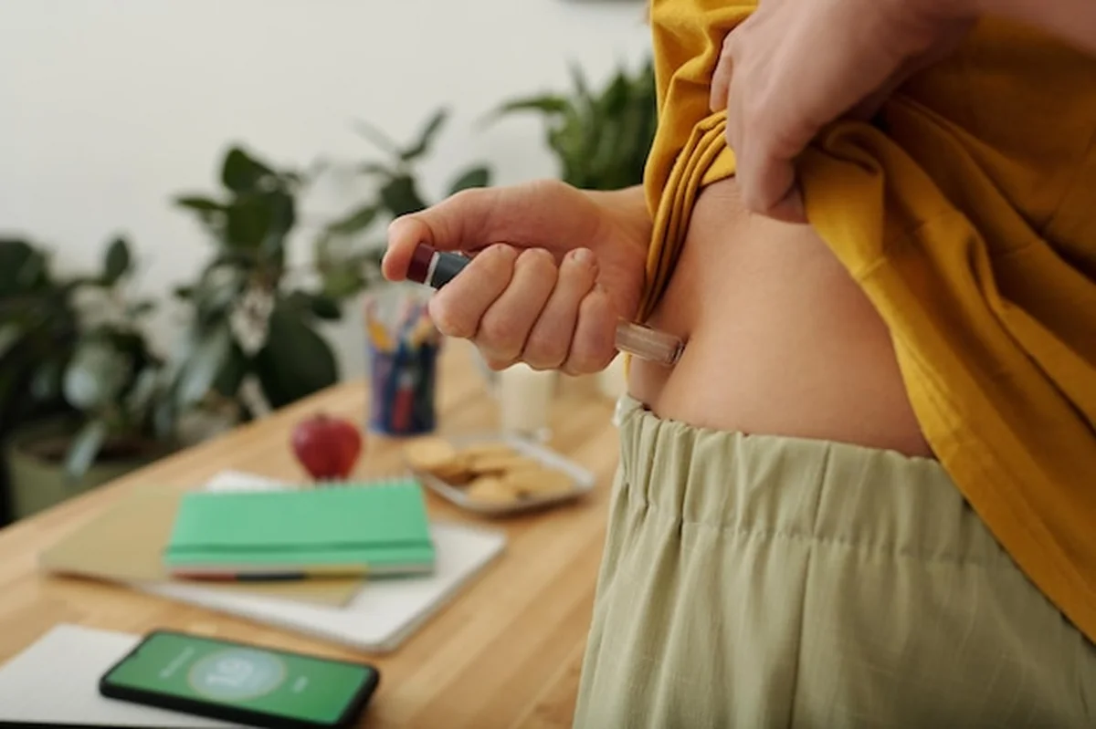 Osoba wstrzykująca insulinę do brzucha za pomocą wstrzykiwacza